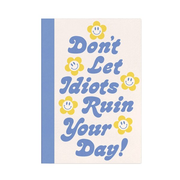 Textured front cover with flowers with the center as a smiley face and purple text saying "Don't Let Idiots Ruin Your Day!"